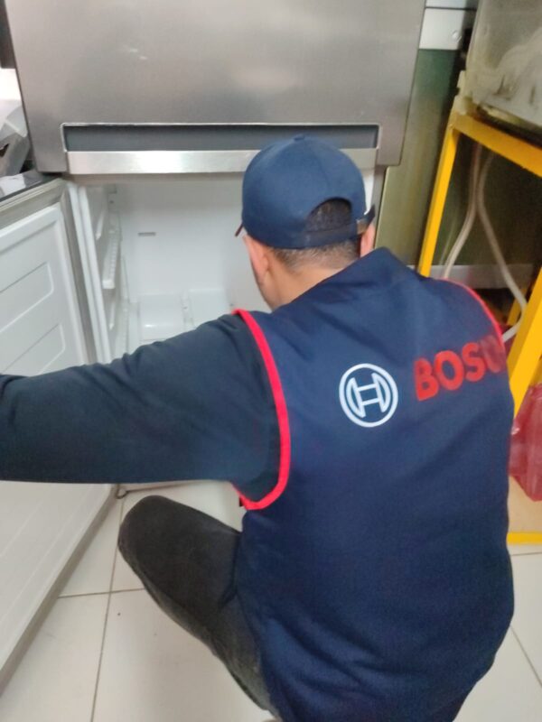 Technicien agréé Bosch réparant un réfrigérateur congélateur